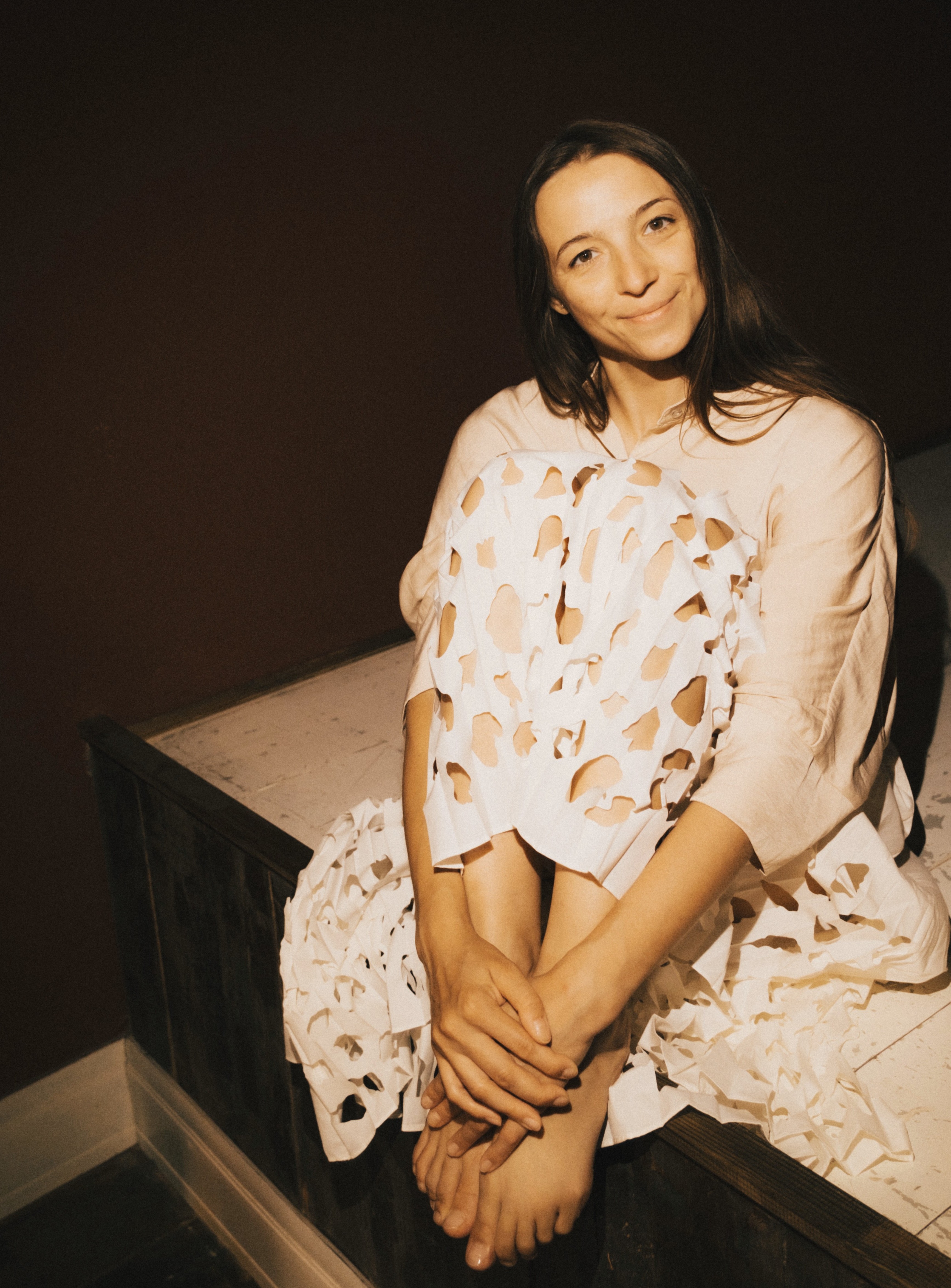 Olya Falina, yoga teacher and wellness coach, sitting calmly on a wooden bench